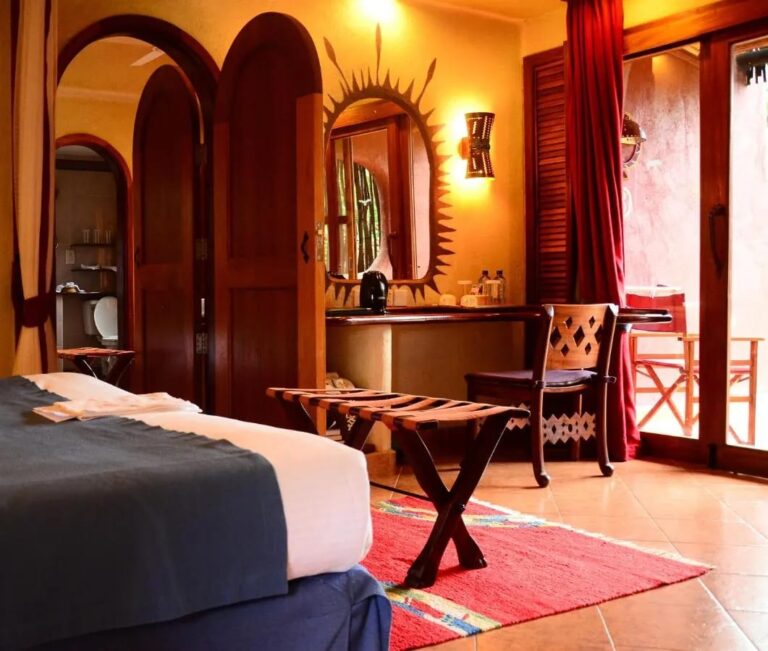 Une chambre aux portes en arc, avec un bureau et une porte vitrée ouverte sur la terrasse