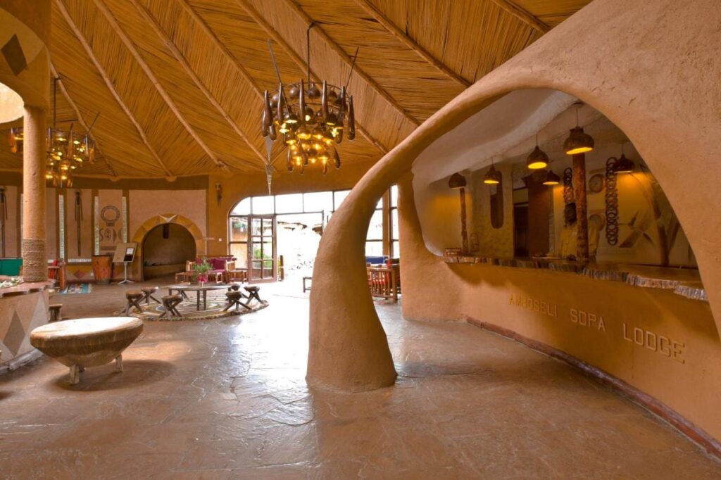 Le comptoir de terre sculptée de la réception, gravé du nom de l'Amboseli Sopa Lodge, sous un plafond de roseaux