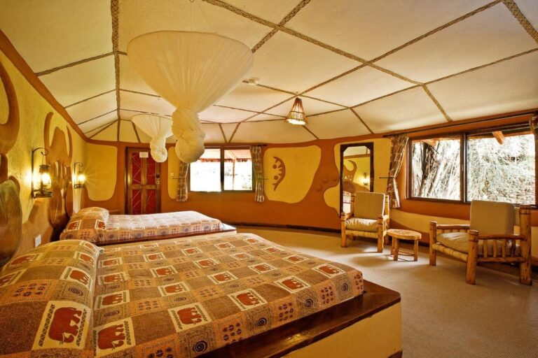 Une chambre à deux lits aux couvre-lits à motifs d'éléphants, sous des moustiquaires nouées au plafond