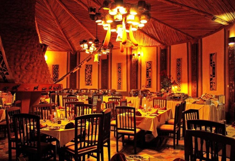 La salle du restaurant le soir, avec des tables nappées de jaune et des lustres allumés