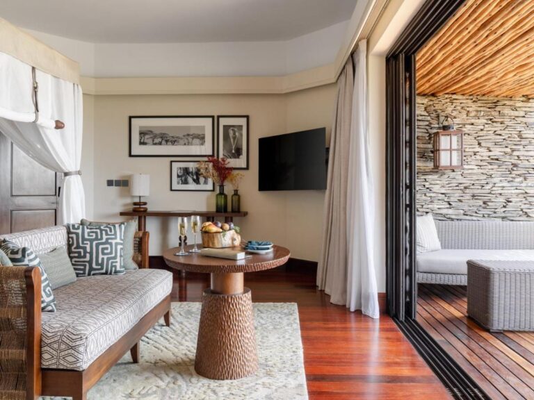 Le coin salon d'une chambre, avec une banquette, deux flûtes sur un guéridon et la terrasse derrière la baie ouverte