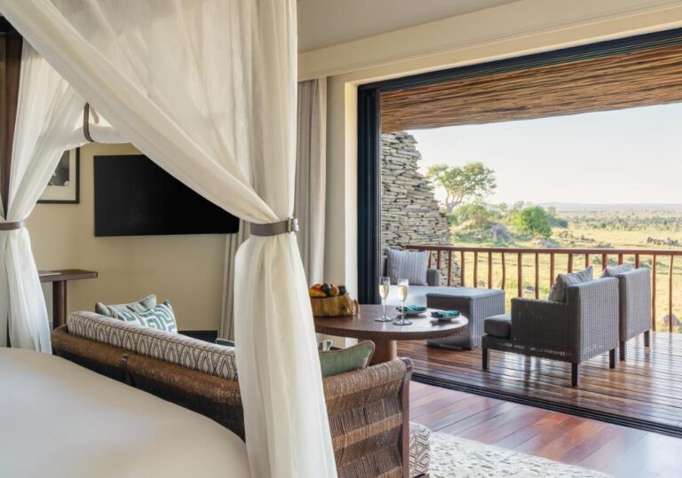 Une chambre ouverte sur sa terrasse et la savane, vue depuis le lit à baldaquin