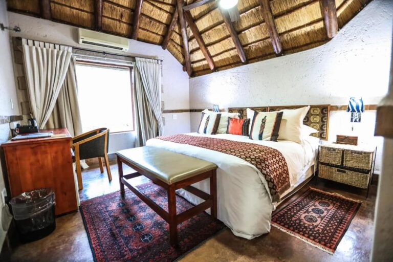 Une chambre sous le chaume, avec la climatisation, un bureau en bois et un banc au pied du lit