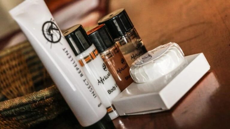 Des produits d'accueil sur une table en bois : savon, lotion pour le corps et répulsif anti-insectes