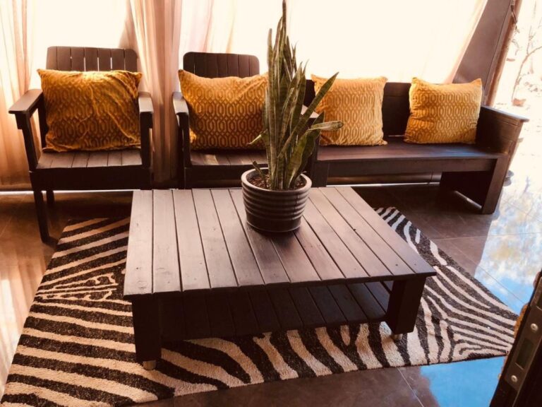 Un salon aux sièges en bois foncé, avec des coussins jaune moutarde et une table basse sur un tapis zébré