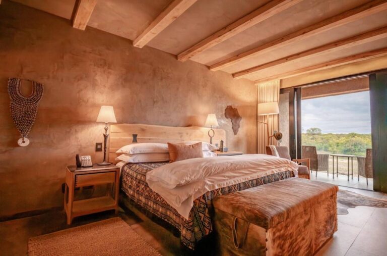 Une suite au grand lit, avec une carte de l'Afrique en bois au mur et une terrasse sur la brousse