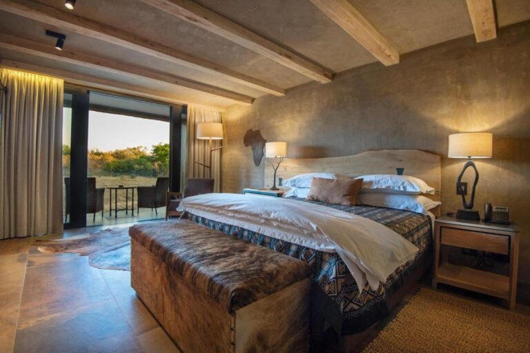 Une suite au grand lit, avec un banc en peau au pied du lit et une terrasse meublée face à la brousse