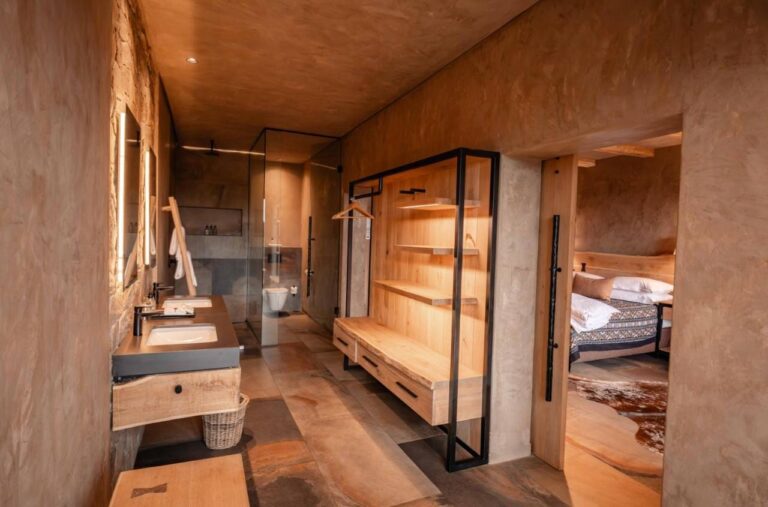 La salle de bains d'une suite, avec douche vitrée, vasque et penderie ouverte