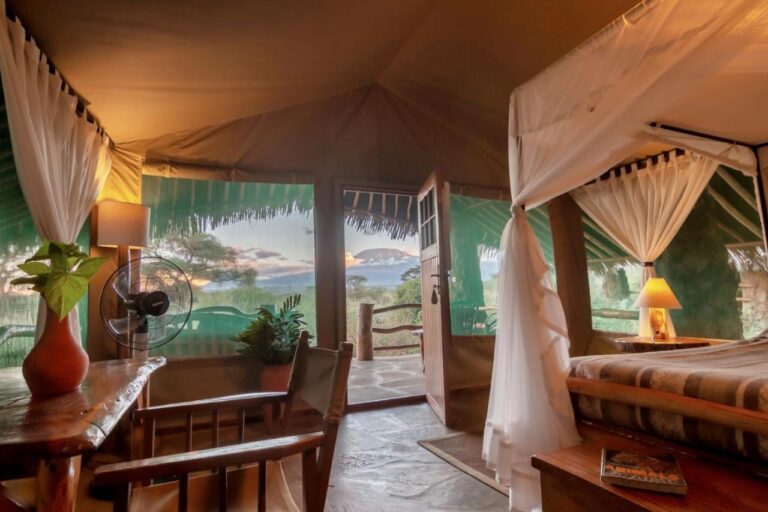 Une tente du Kibo Safari Camp ouverte sur sa terrasse, le Kilimandjaro au loin au crépuscule
