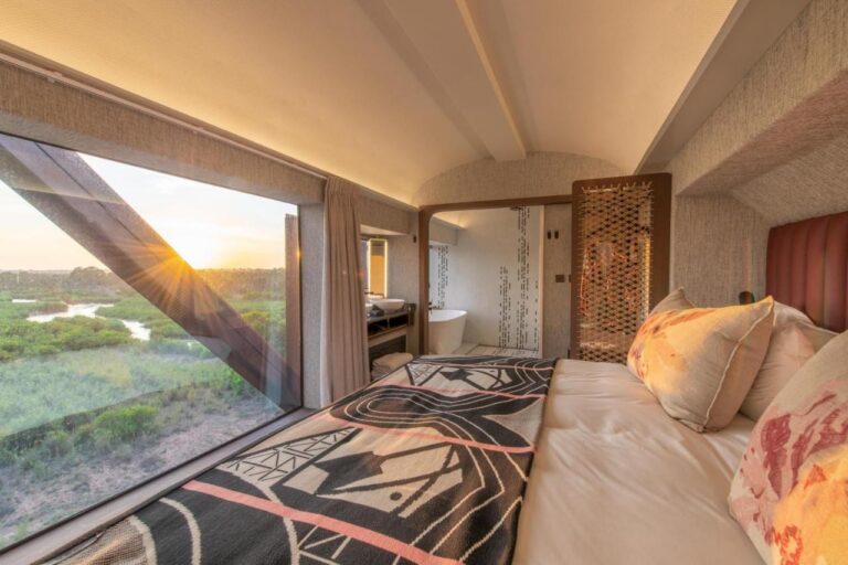 L'intérieur d'un wagon du Kruger Shalati, le lit face à une grande fenêtre sur la rivière et la baignoire au fond