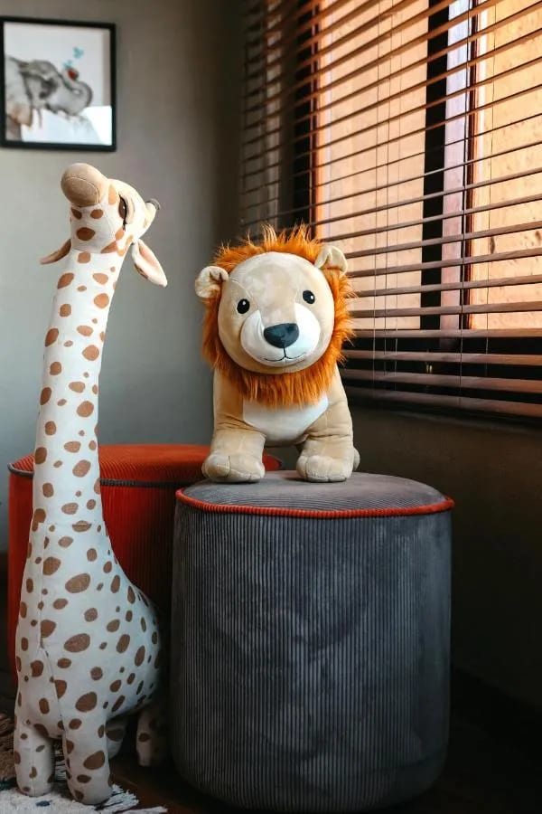 Une girafe et un lion en peluche près d'une fenêtre à stores