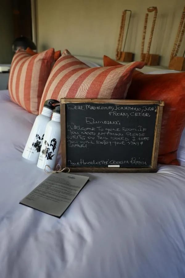 Un mot de bienvenue écrit à la craie sur une ardoise, posée sur le lit avec deux gourdes