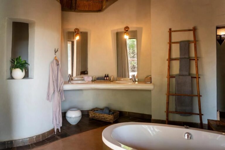 Une salle de bains aux murs arrondis, avec une baignoire, deux vasques et une échelle porte-serviettes