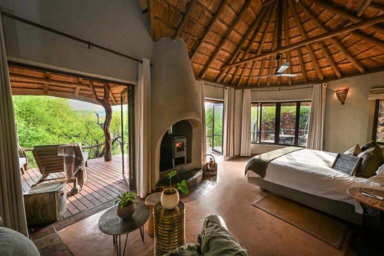 Une suite ouverte sur une terrasse face aux arbres, avec un poêle à bois et un grand lit