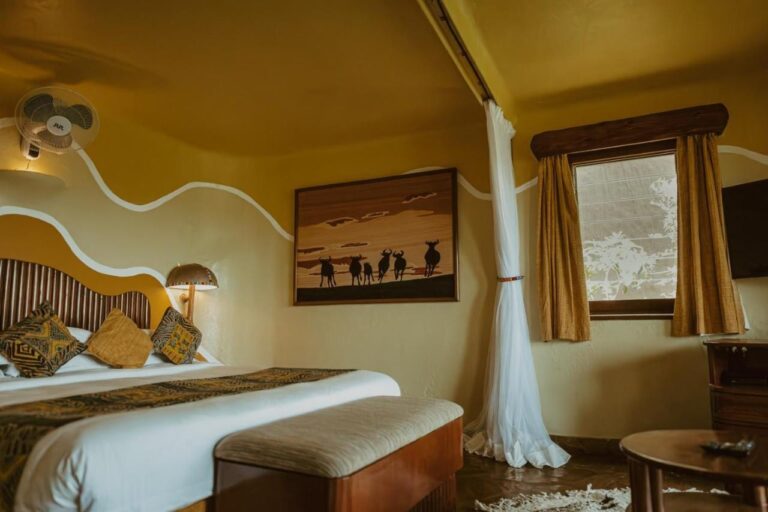 Une chambre avec un tableau de gnous en silhouette au-dessus du lit et un ventilateur mural