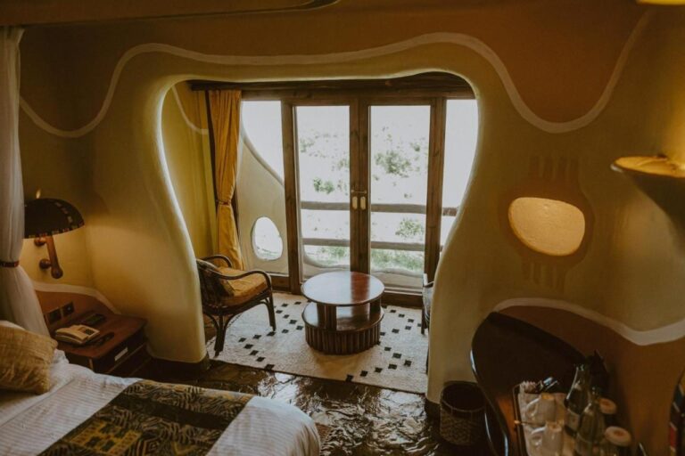 Une chambre aux murs arrondis du Mara Serena Safari Lodge, avec un coin salon devant la porte-fenêtre du balcon