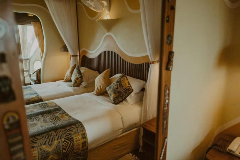 Les deux lits d'une chambre jumelle, vus dans un miroir au cadre de bois sculpté