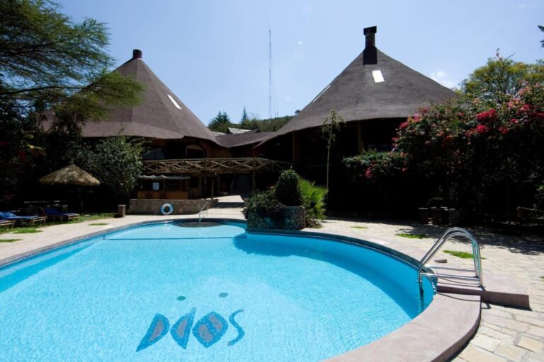 La piscine du Mara Sopa Lodge, devant des bâtiments aux grands toits coniques en chaume