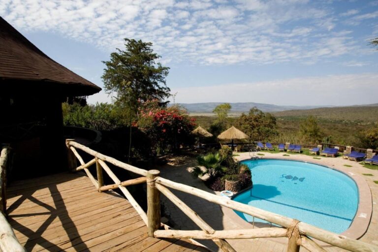 La piscine du Mara Sopa Lodge vue d'une terrasse en bois, face à la brousse et aux collines