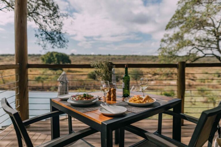 Un repas servi sur une table de la terrasse en bois, face à la brousse