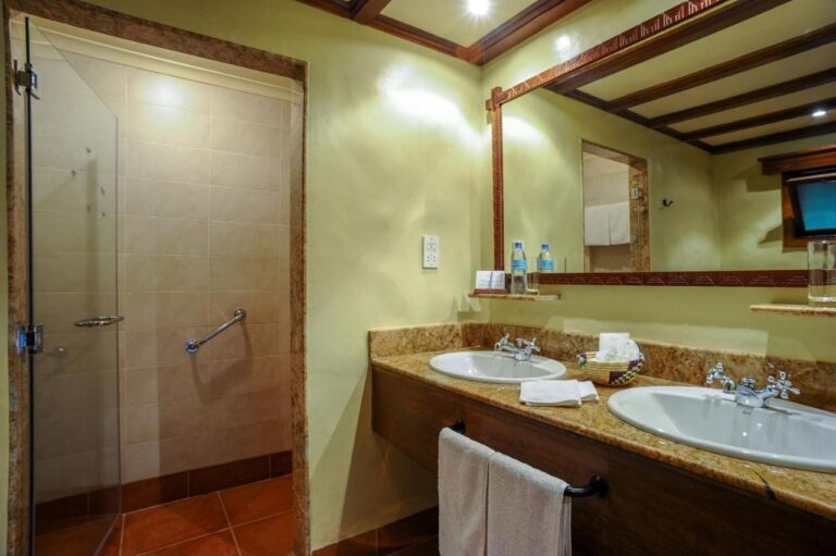 Une salle de bains avec deux vasques et une douche vitrée