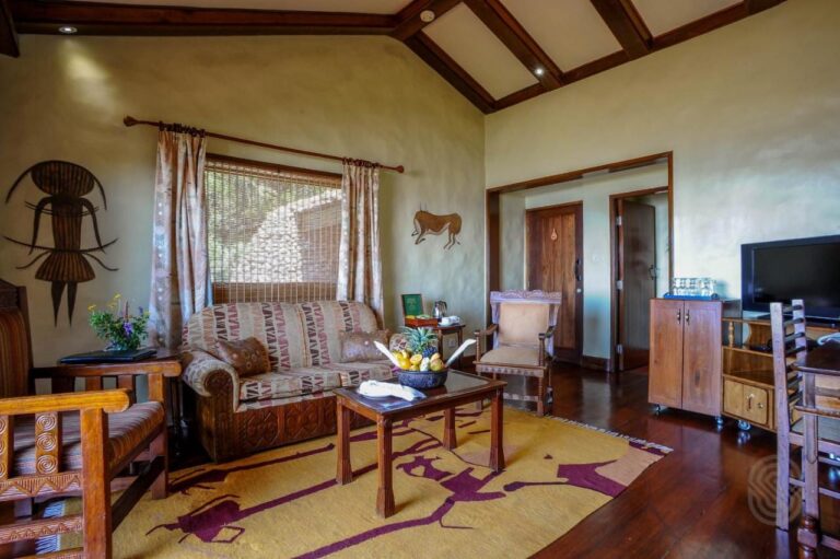 Le salon d'une suite, avec des fauteuils en bois sculpté et un tapis jaune à motifs