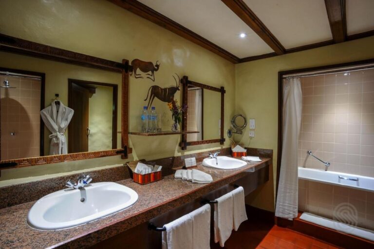 Une salle de bains avec deux vasques, une baignoire et un peignoir suspendu