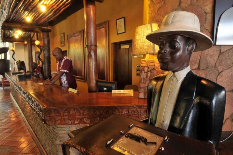 La réception, avec un comptoir sculpté et la statue en bois d'un homme coiffé d'un casque colonial