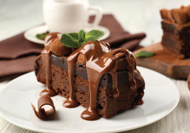 Une part de gâteau au chocolat nappée de sauce, avec des feuilles de menthe
