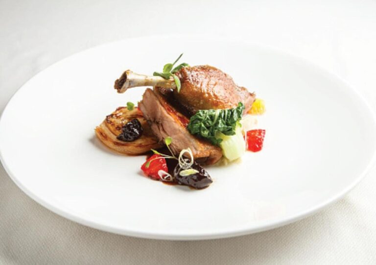 Une cuisse de volaille rôtie et ses légumes sur une assiette blanche