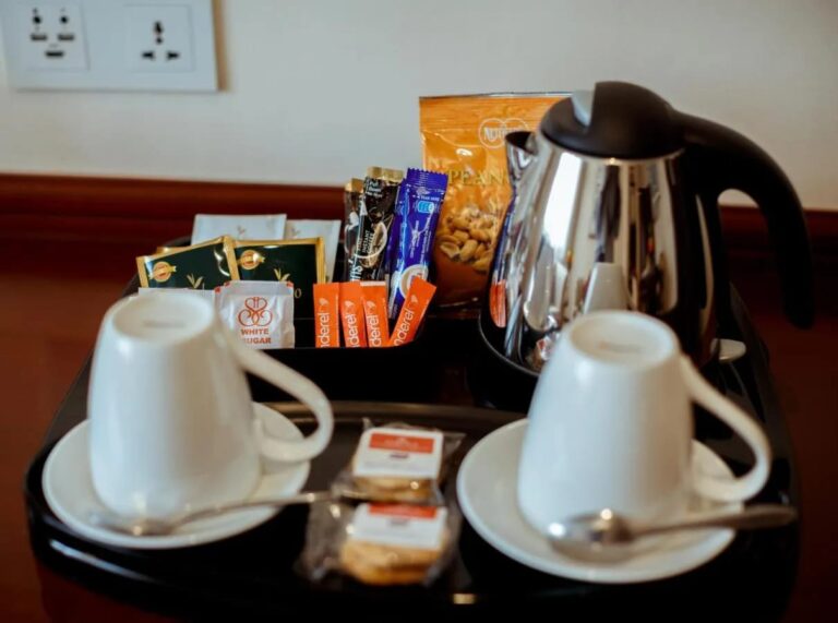 Un plateau avec bouilloire, deux tasses, du thé, du café en sachets et des biscuits