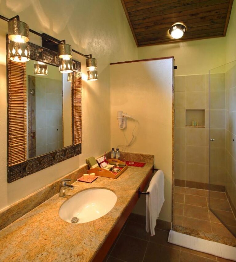 Une salle de bains avec un plan de toilette en granit, un sèche-cheveux et une douche vitrée