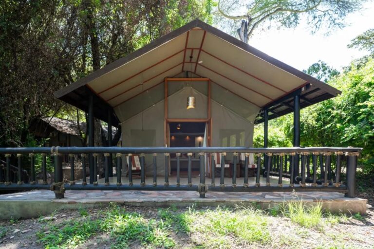 Une tente du Sarova Mara Game Camp sous son toit, sur une terrasse à balustrade, entre les arbres