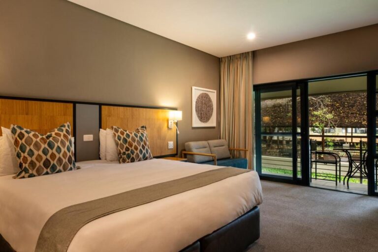Une chambre avec un grand lit et un canapé, ouverte sur un balcon meublé