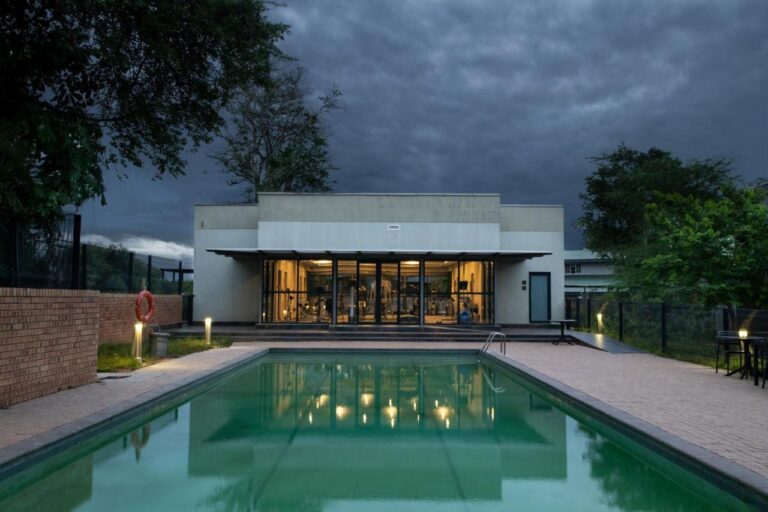 La piscine extérieure devant la salle de fitness vitrée, sous un ciel d'orage
