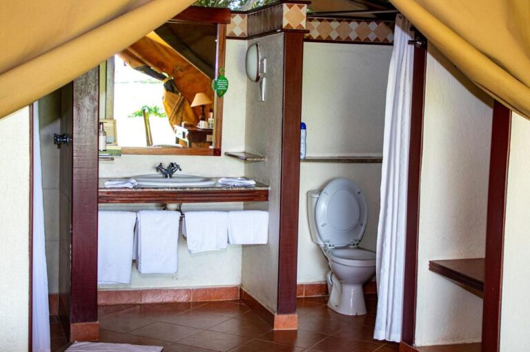 La salle de bains d'une tente, avec lavabo, toilettes et rideau de douche