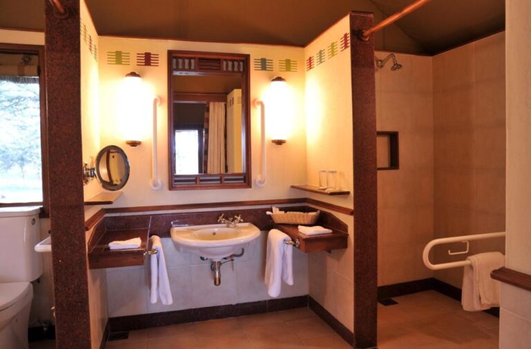Une salle de bains adaptée, avec barres d'appui, lavabo et douche de plain-pied