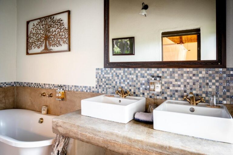 Une salle de bains avec deux vasques sur un plan en béton, une baignoire et une crédence en mosaïque