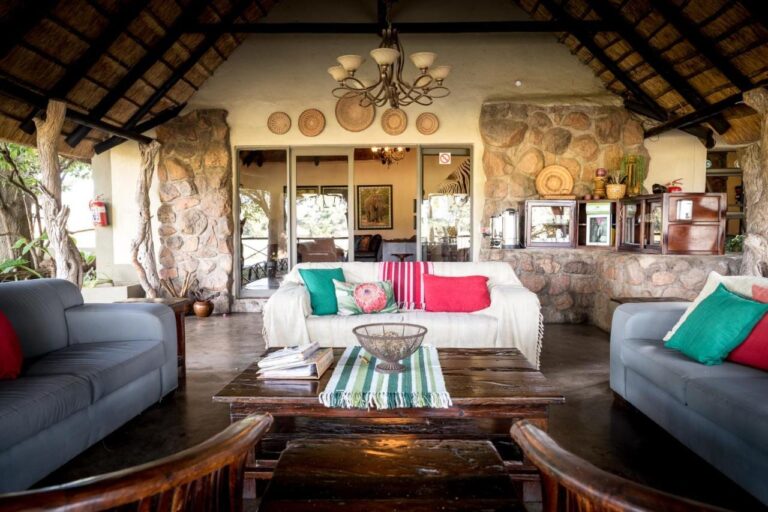 Le salon ouvert de l'Umkumbe Safari Lodge, sous le chaume, avec des canapés gris et des murs de pierre
