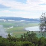 Le fond vert du cratère vu depuis le rebord, avec le lac Magadi et des nuages accrochés aux parois